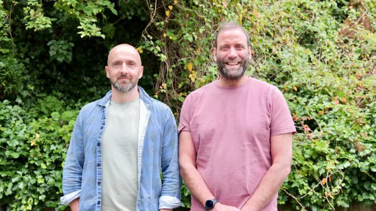 Founders of WasteSync in front of green hedge.