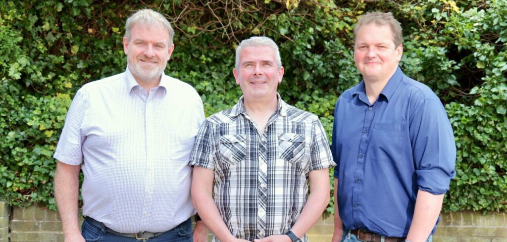 founders of settlz, three men, stand in front of wall and foliage at meadowbank house